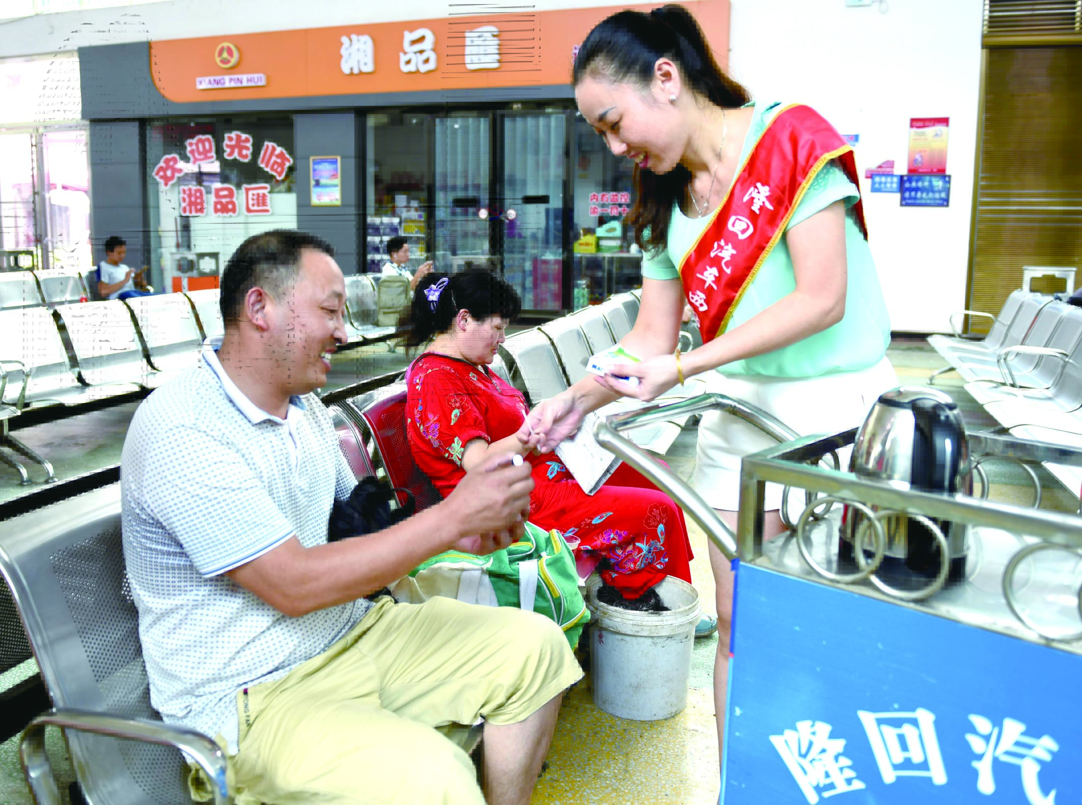 隆回分公司汽車西站工作人員正在為旅客免費(fèi)贈(zèng)送藿香正氣水。